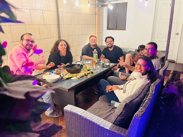 Huéspedes cenando juntos en la terraza, de noche y con luces de colores